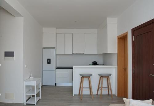 una cucina con armadi bianchi e 2 sgabelli da bar di Comfort and Peace a Santa Maria