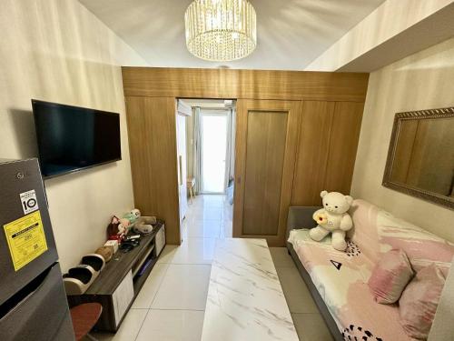 a living room with a teddy bear sitting on a couch at Shell Residence MOA Pasay by Kathy in Manila