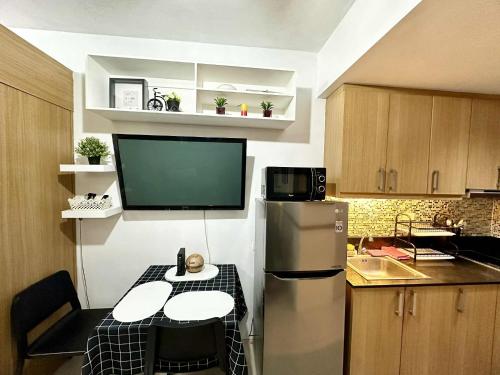 a kitchen with a refrigerator and a table in it at Shell Residence MOA Pasay by Kathy in Manila
