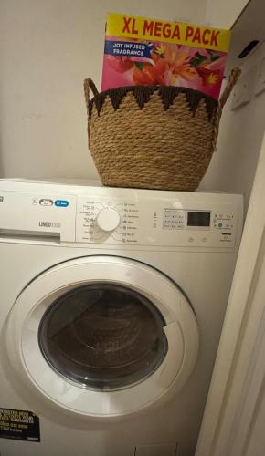 a microwave with a basket on top of a washing machine at Luxury flat with FREE parking & easy tube access! in London