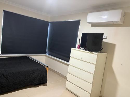 a bedroom with a bed and a tv on a dresser at 3x1 unit at back of main house in Spearwood
