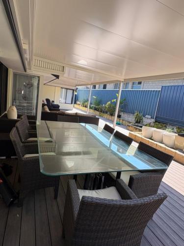 a glass dining table and chairs in a room at 3x1 unit at back of main house in Spearwood