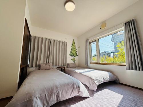 een slaapkamer met twee bedden en een groot raam bij Kamui Adventure House in Asahikawa