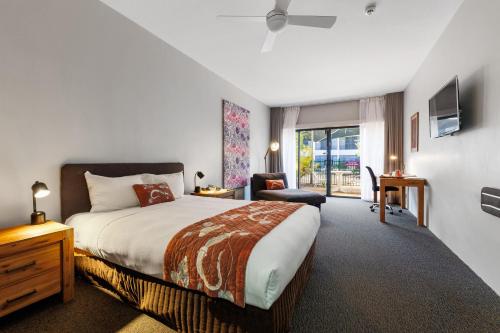 Un dormitorio con una cama, una silla y una ventana en Mercure Kakadu Crocodile, en Jabiru