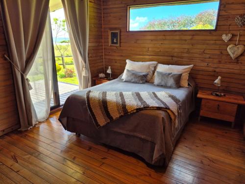 a bedroom with a bed with a window and a wooden wall at Villa Maori Tea Rapa Nui, Easter Island with ocean view in Hanga Roa