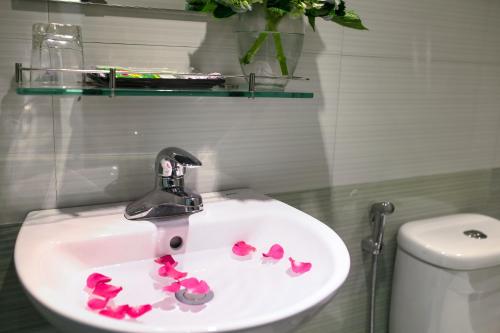 a bathroom sink with pink petals on it at Hanoi Golden Hotel in Hanoi