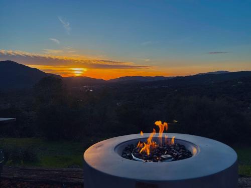een vuurplaats met mensen erin met de zonsondergang bij Relax Under the Stars, Best view in town , Yosemite House with Firepit, Hot Tub, Game Room & Pool table in Oakhurst