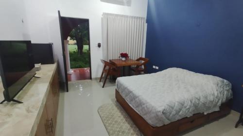 a bedroom with a bed and a tv and a table at Casa Mangos in Mérida