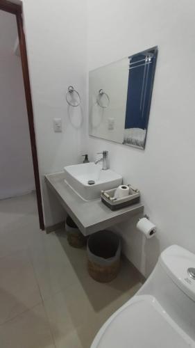 a white bathroom with a sink and a toilet at Casa Mango in Mérida