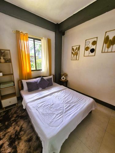 a bedroom with a large white bed with a window at 88 Tourist Inn by Lagum Adventure in Coron