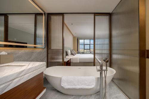 a bathroom with a bath tub and a bedroom at WYNDHAM TAIYUAN in Taiyuan