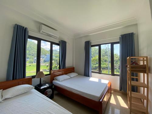 a bedroom with two beds and large windows at Cat Ba Rustic Homestay in Cat Ba