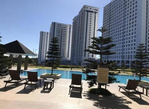 a pool with chairs and tables and buildings at Idyllic Taal with Modern Vibe 2BR Condo Stunning View - Netflix - 3AC - WiFi in Tagaytay