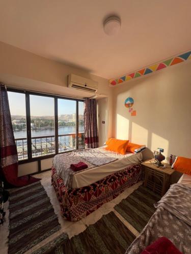 a bedroom with two beds and a large window at NubaNest GuestHouse in Aswan