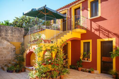 a yellow and orange house with a staircase and an umbrella at Hotel Baglio Catalano in Custonaci