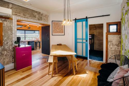 a kitchen and living room with a wooden table at Fun Times in Fitzroy - eclectic bungalow by beach in New Plymouth