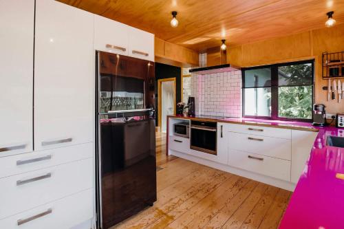 a kitchen with white cabinets and pink appliances at Fun Times in Fitzroy - eclectic bungalow by beach in New Plymouth