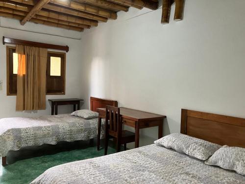 InzáLa Portada en Tierradentro Restaurante y Hospedaje的一间卧室，有两张床、一张书桌和一张桌子