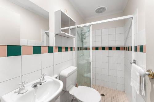 Un baño blanco con inodoro y lavabo. en Box Hill Studio Apartment 2, en Box Hill