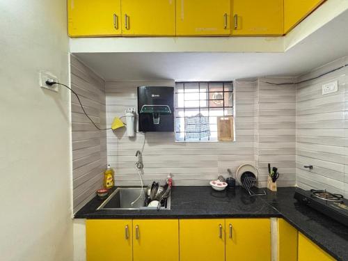 een keuken met gele kasten en een wastafel bij Ideal 2BHK for Families & Work Trips in Bangalore