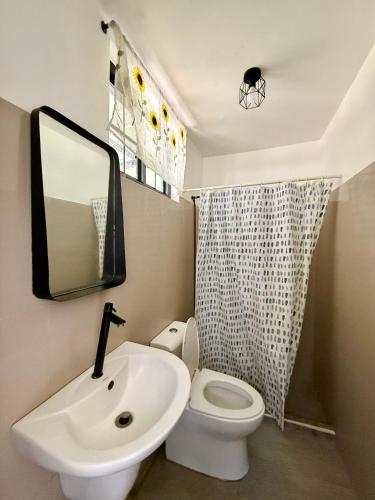 ein Badezimmer mit Waschbecken, Toilette und Spiegel in der Unterkunft Bloom&Blossom in Iloilo City