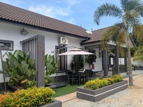 カンポン・ペナリックにあるAG Suitesの庭のテーブルと傘を持つ家