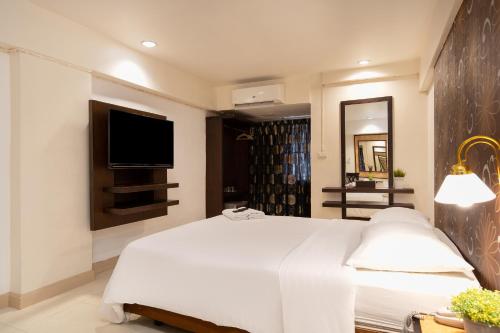 a bedroom with a white bed and a television at Synsiri Lat Phrao 83 in Ban Zong Katiam