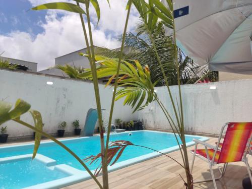 a pool with a chair and a plant next to it at Casa de condomínio em Paripueira com piscina e perto da praia in Paripueira