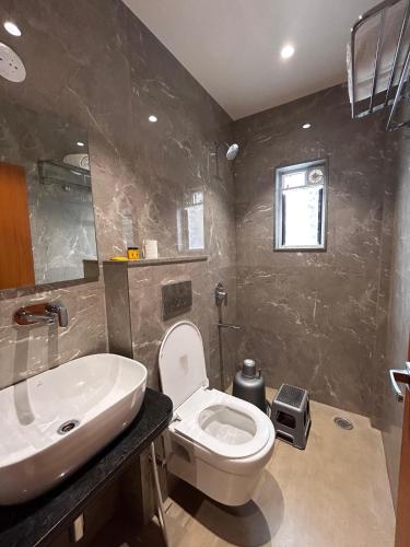 a bathroom with a white toilet and a sink at Hotel Neem Heritage in Shirdi