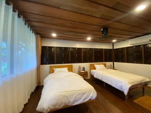 a bedroom with two beds and a large window at Dalasone Pool Villas with Stunning Mountain Views in Vang Vieng