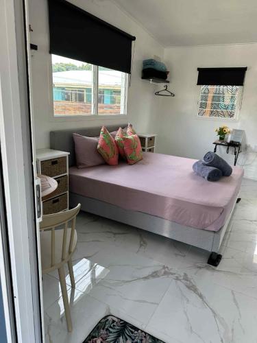 a bedroom with a bed with pink sheets and a window at Sharnyta's Studio Aitutaki in Amuri