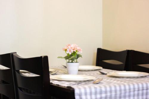 una mesa con platos y un jarrón de flores. en Comfort Homey Studio with Fresh Mountain Air by Cherisia's Hideaway, en Baguio