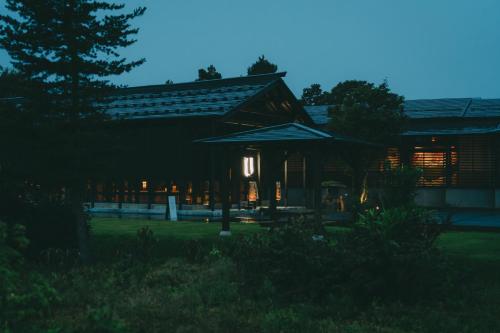 a building with an umbrella in front of it at 泊まれる文化交流施設 盆宿U bon-yadoU in Nishimonai
