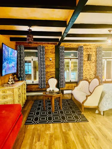 a living room with white chairs and a tv at Gîte du monde in Quebec City