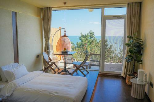 een slaapkamer met een bed en een balkon met uitzicht bij Qingdao Momer Cliff Ocean View Villas in Qingdao