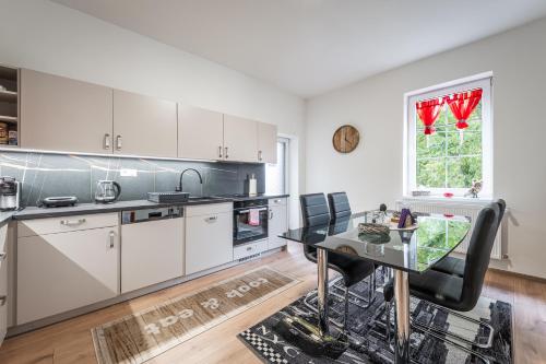 a kitchen with white cabinets and a glass table at Elements Apartments & Renata in Božičany