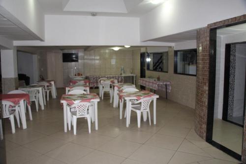 un comedor con mesas blancas y sillas blancas en Comfoort Hotel en Volta Redonda