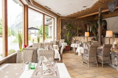 a restaurant with tables and chairs and windows at Raffl's Hotel in Leutasch