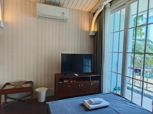 a bedroom with a bed and a tv and a window at Grand Florida芭提雅带免费游泳池温泉和健身房和办公区水上花园公寓E208 in Na Jomtien