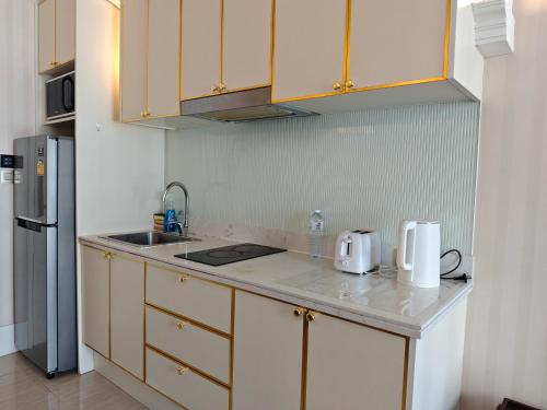 a kitchen with yellow cabinets and a counter top at Grand Florida芭提雅带免费游泳池温泉和健身房和办公区水上花园公寓E208 in Na Jomtien
