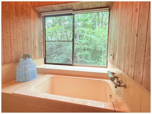 a bath tub in a room with a window at コテージちゃ豆ん家 in Nasu