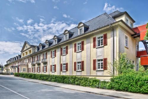 a large building with red shuttered windows on a street at Santé Royale Hotel- & Gesundheitsresort Bad Brambach in Bad Brambach