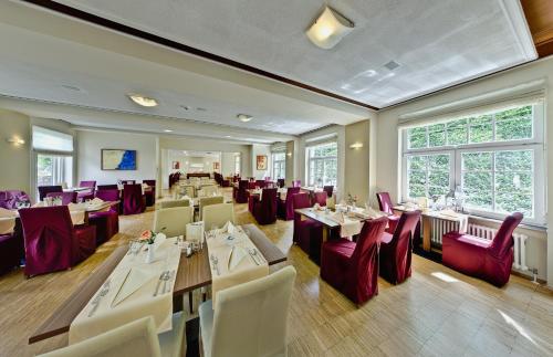 a restaurant with white tables and red chairs at Santé Royale Hotel- & Gesundheitsresort Bad Brambach in Bad Brambach