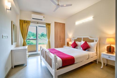 a bedroom with a white bed and a window at Cozy 2BHK Pool Apartment in candolim in Candolim