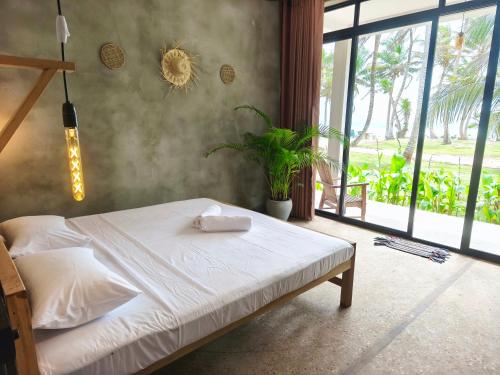Un dormitorio con una cama y una ventana grande. en Surfescape Sri Lanka, en Midigama East