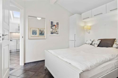 een witte slaapkamer met een wit bed en een keuken bij Lovely Holiday Home Near Hasmark Beach in Otterup