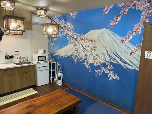 a kitchen with a mountain mural on the wall at 新規オープン岩風呂付ゲストハウス織姫 in Fujiyoshida