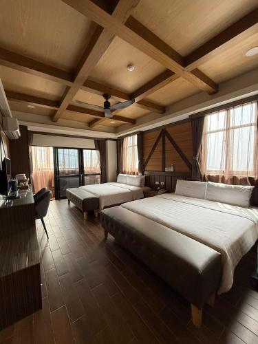a bedroom with two beds and a table and windows at Gaodiyuan Tea B&B 高帝園茶業民宿 in Meishan