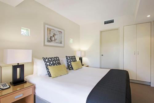 a bedroom with a large white bed and a telephone at Mantra French Quarter Noosa in Noosa Heads