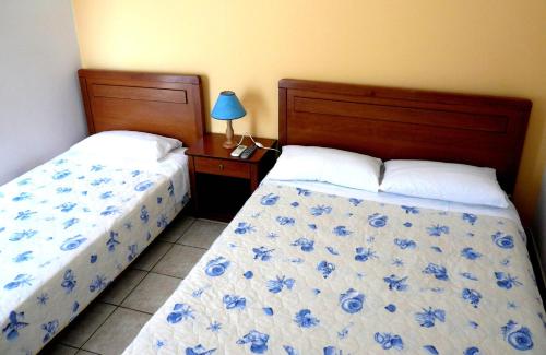 a bedroom with two beds and a table with a lamp at Peter & Tony Rooms in Galissas